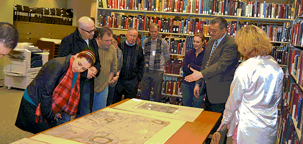 A group of people in a library around table with a map on it